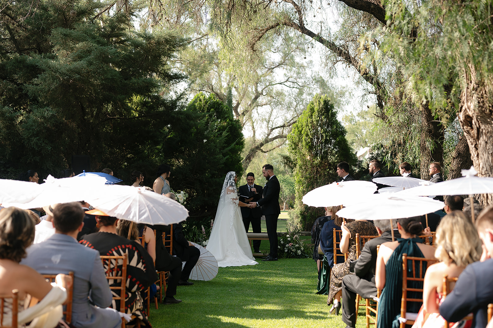 Bride and groom exchanging vows under trees at outdoor San Miguel de Allende wedding