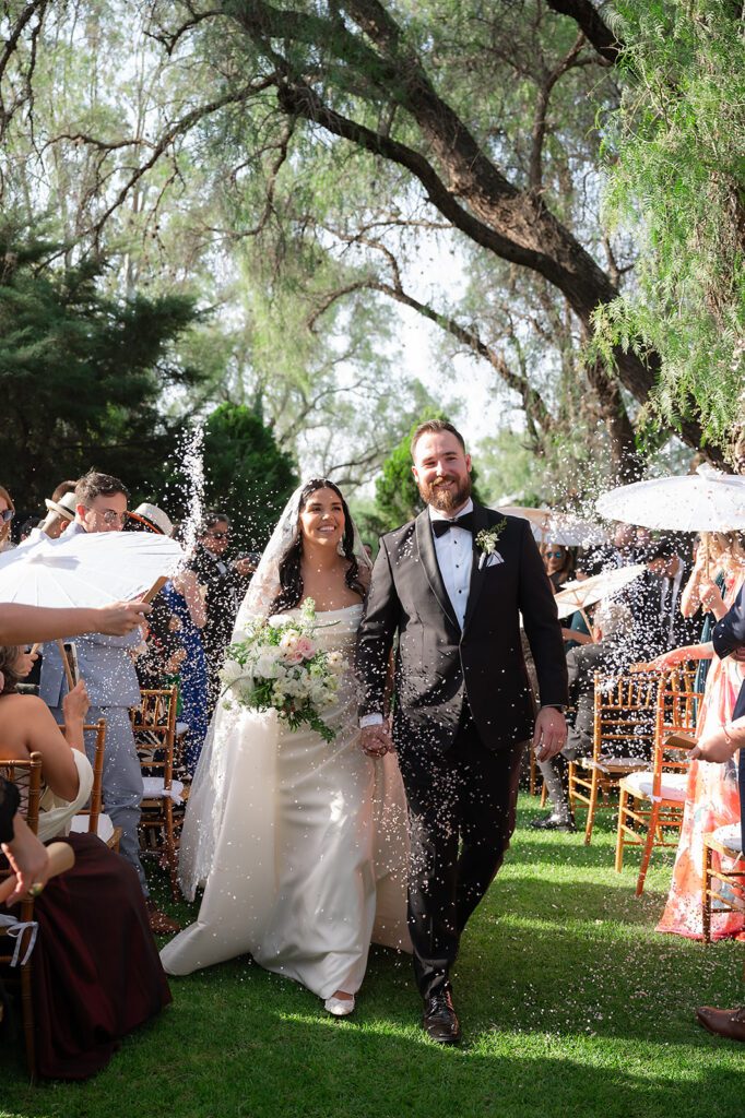 Bride and groom walking back up the aisle as guests toss rice after San Miguel de Allende wedding ceremony