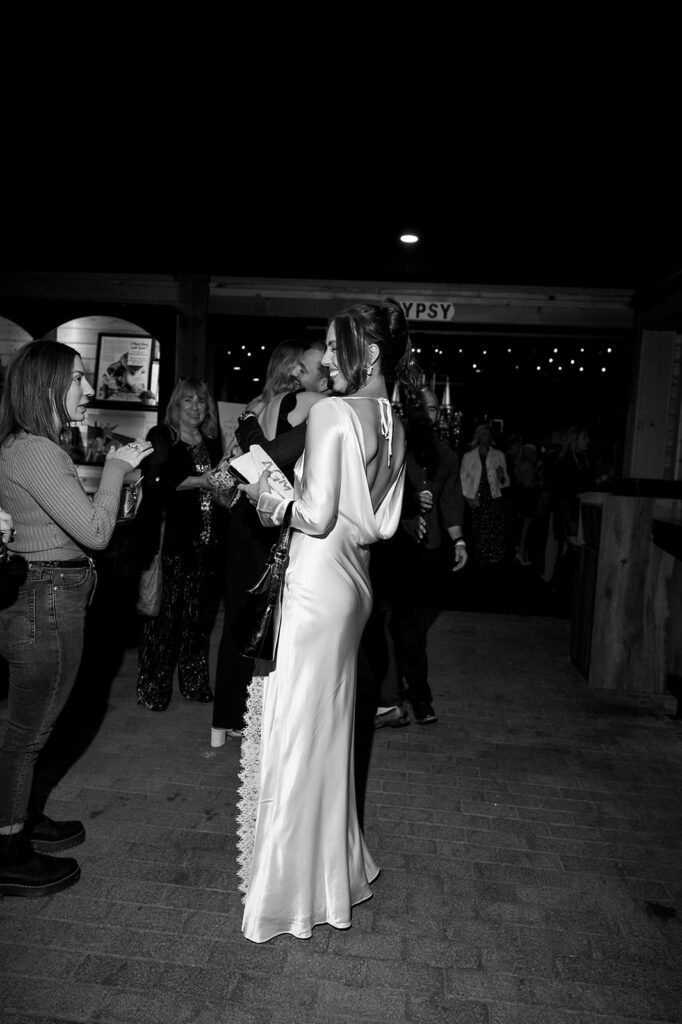 Black and white flash photo of a bride mingling with guests during their welcome wedding party