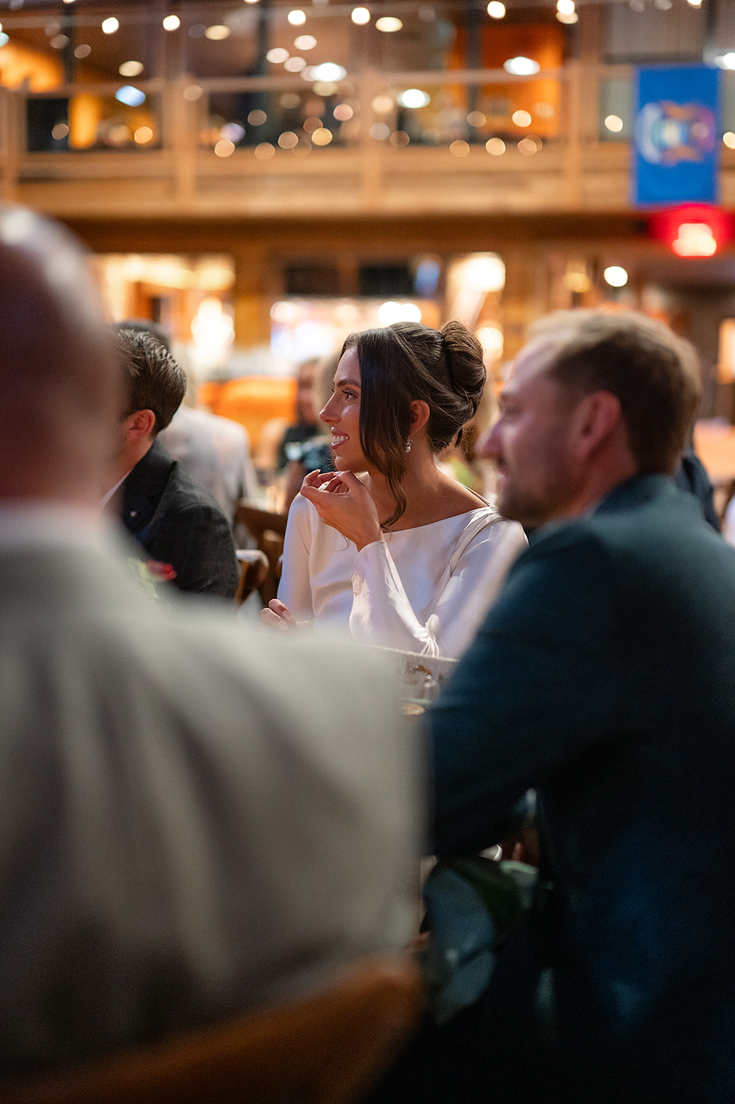 Bride and groom smiling during dinner at the Bay Harbor welcome party with soft lighting and a relaxed, elegant atmosphere.