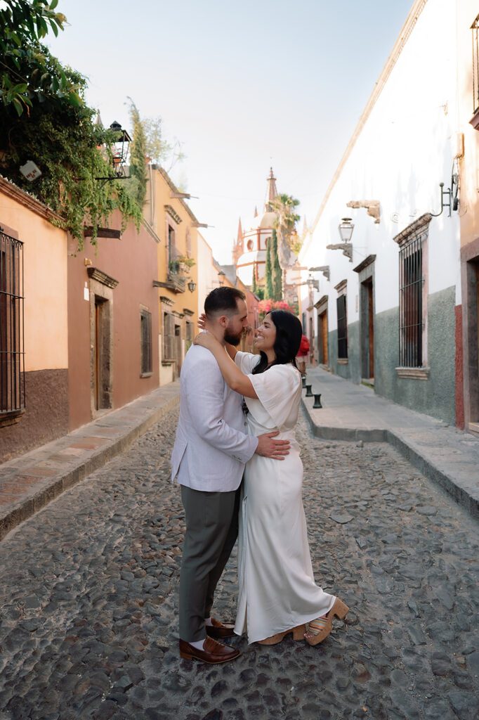 Couple posing in the cobblestone streets of San Miguel de Allende with Parroquia de San Miguel Arcángel in the background.