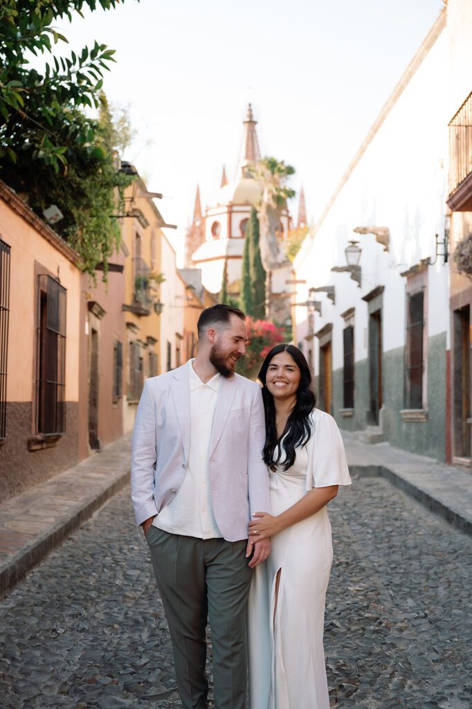 Couple shares a quiet moment in the cobblestone streets of San Miguel de Allende with Parroquia de San Miguel Arcángel in the background.