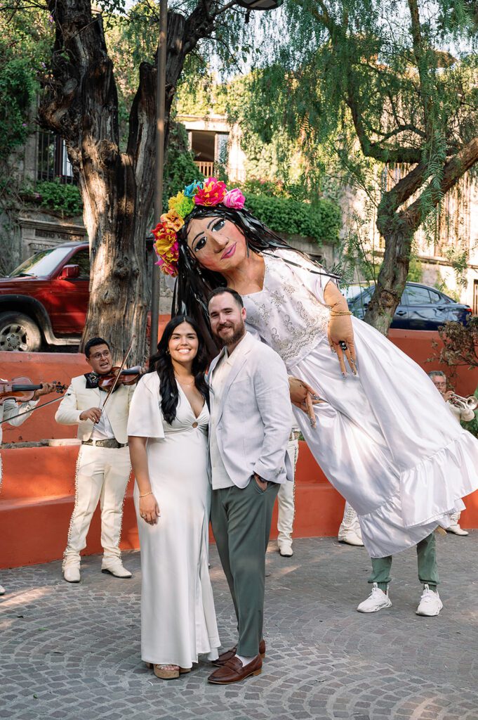 Traditional giant puppet, known as mojigangas, pose with the couple during the callejoneada parade in San Miguel de Allende.