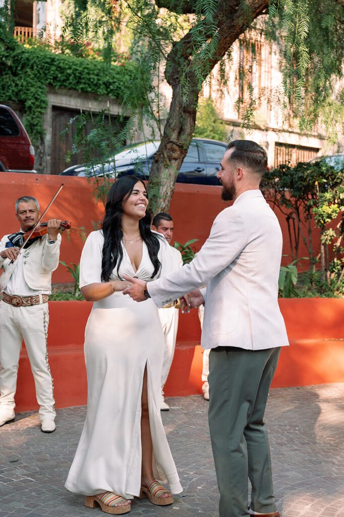 Couple dancing during their callejoneada parade during their San Miguel de Allende wedding celebration through tree-lined streets.