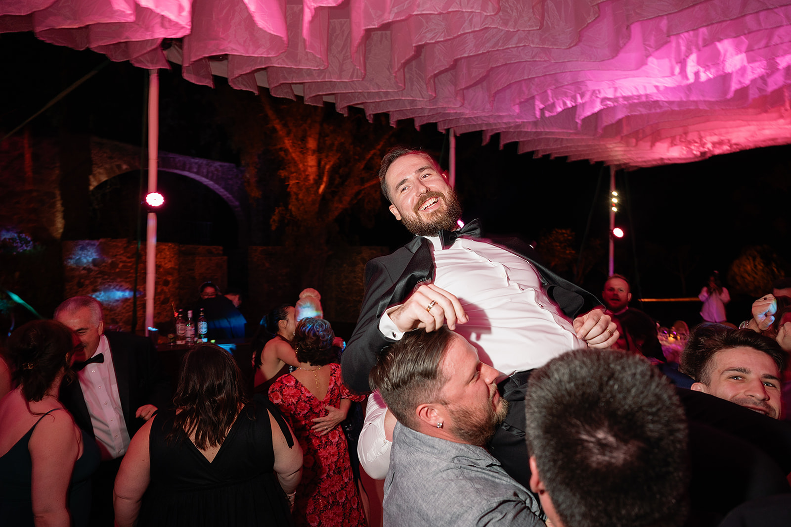 Groom being lifted in the air by guests during lively dance party under the tent at Hacienda San Luis Gonzaga wedding.