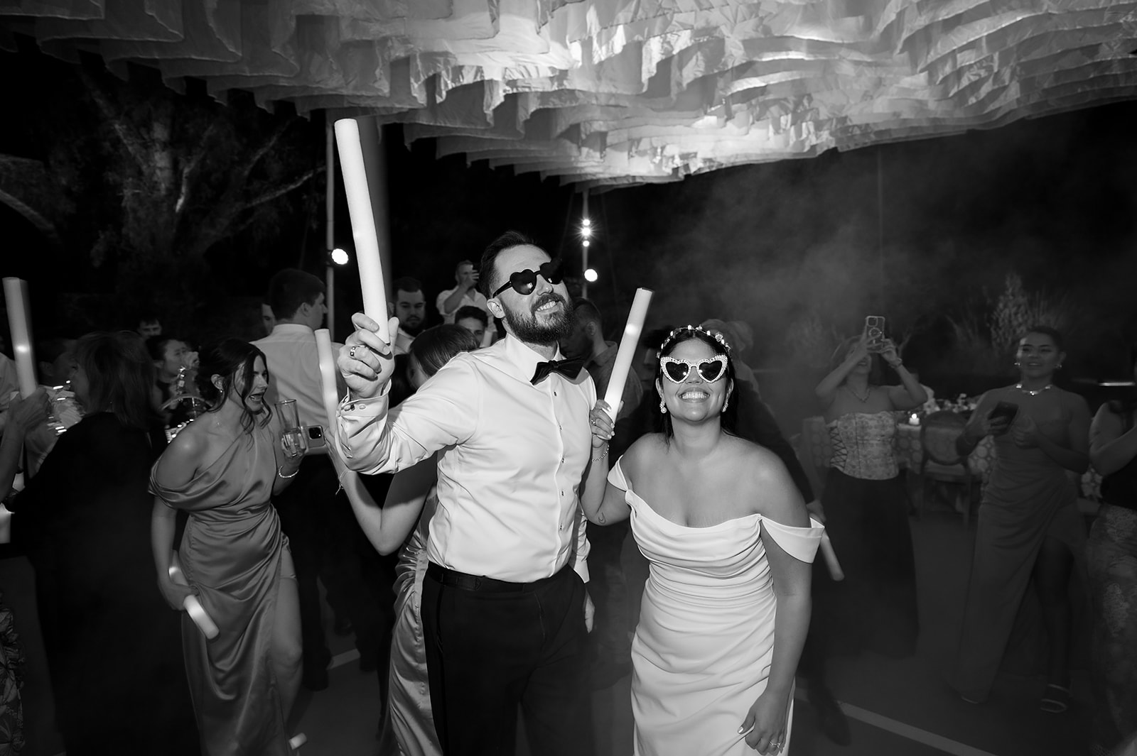 Bride and groom dancing with glow sticks surrounded by guests under tented reception lighting at Hacienda San Luis Gonzaga.