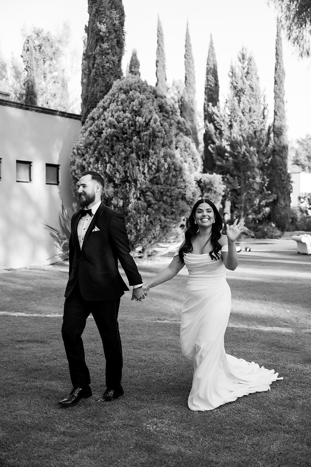 Bride and groom walking hand-in-hand and smiling before entering their Hacienda San Luis Gonzaga reception.