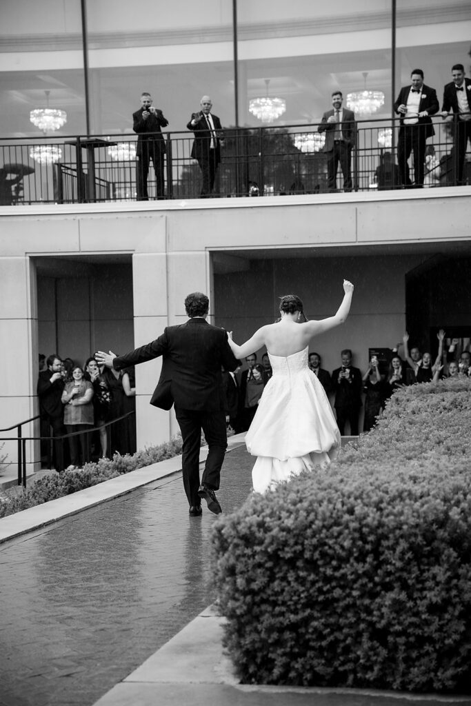Black and white photo of a bride and groom walking to Grosse Pointe War Memorial after their first dance.