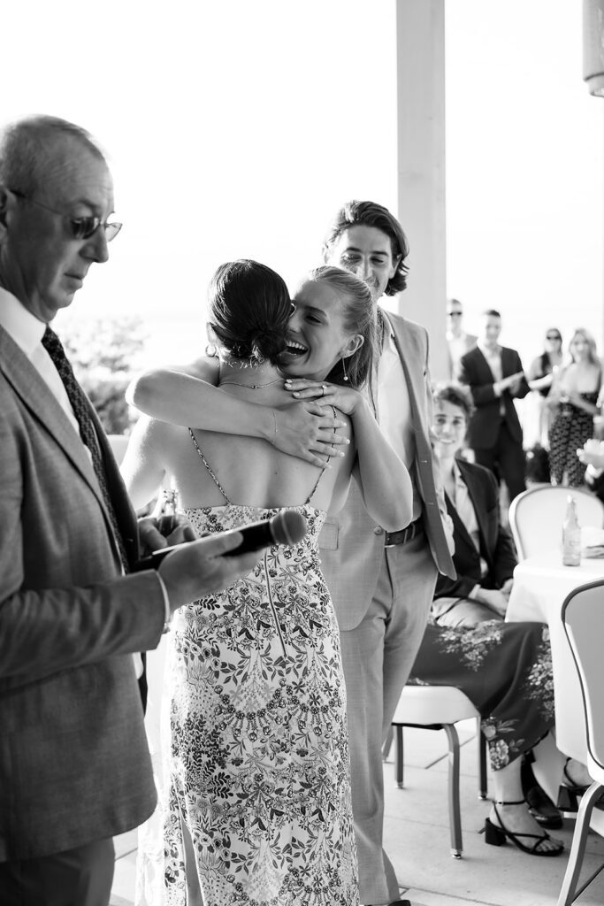 Bride embracing a guest during a heartfelt speech at the Delamar welcome party in Northern Michigan.