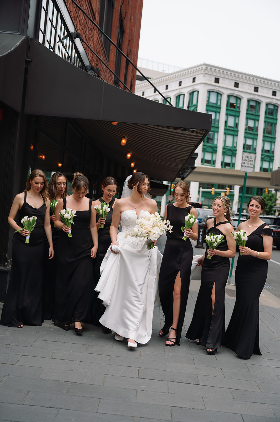 Bride and bridesmaids walking together in downtown Detroit during wedding portraits near the Shinola Hotel.