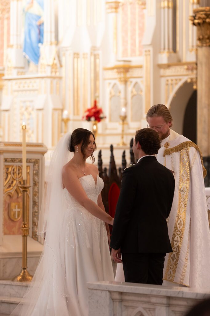 Bride and groom holding hands at the altar during a traditional Detroit church wedding.