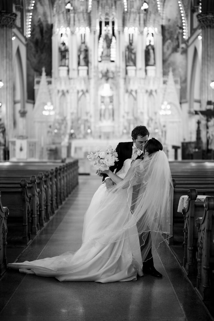 Bride and grooms end of aisle dip kiss at Sweetest Heart of Mary Church in Detroit.