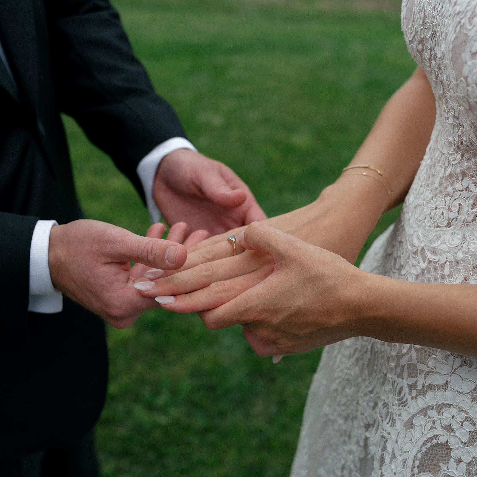 Close-up of the groom holding the brides hand with her engagement ring on.
