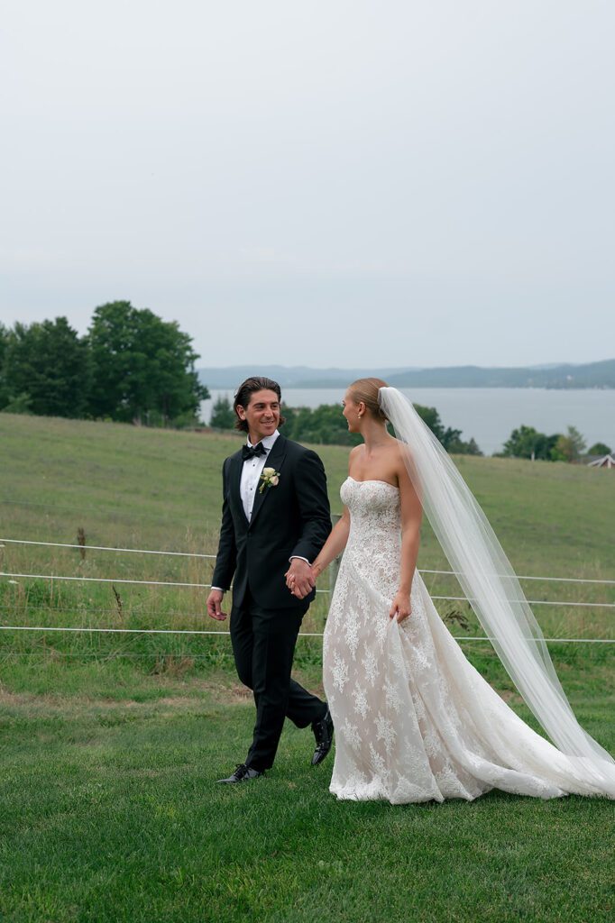 Bride and groom walk hand in hand during wedding portraits at Noverr Farms in Traverse City, Michigan.