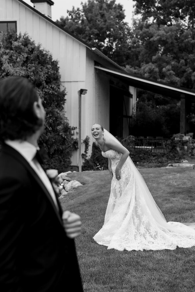 Candid black and white photo of a bride and groom laughing together at Noverr Farms.