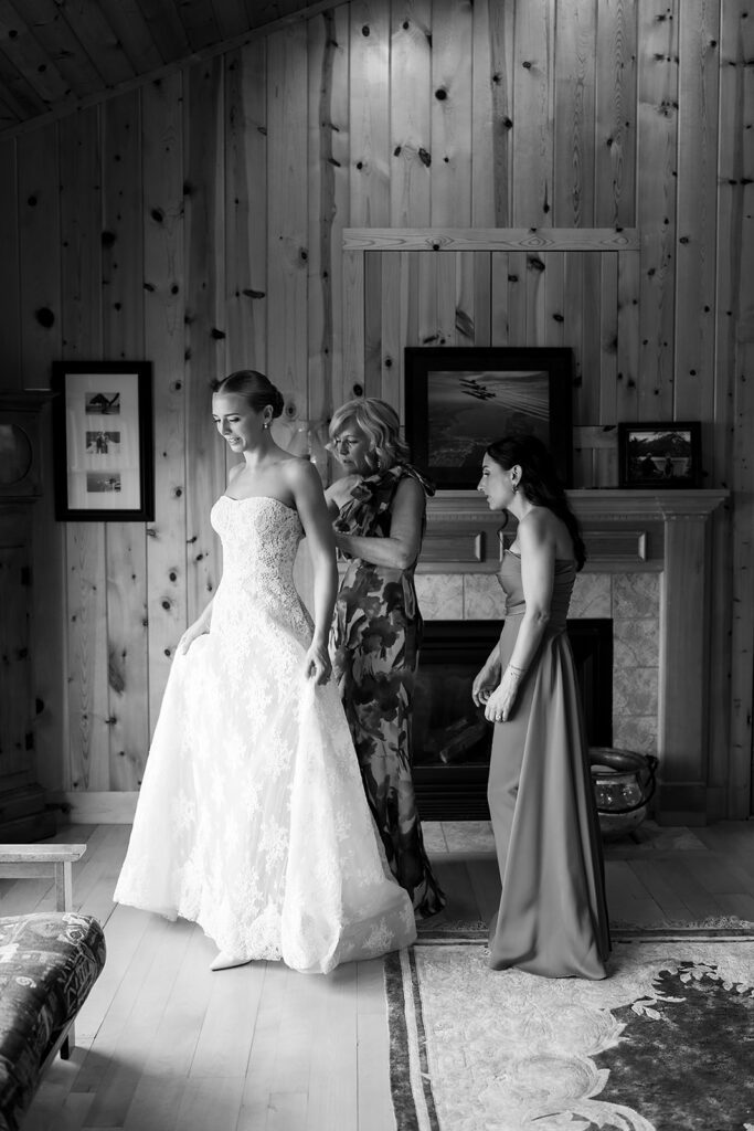 Bride being helped into her wedding gown by family members.