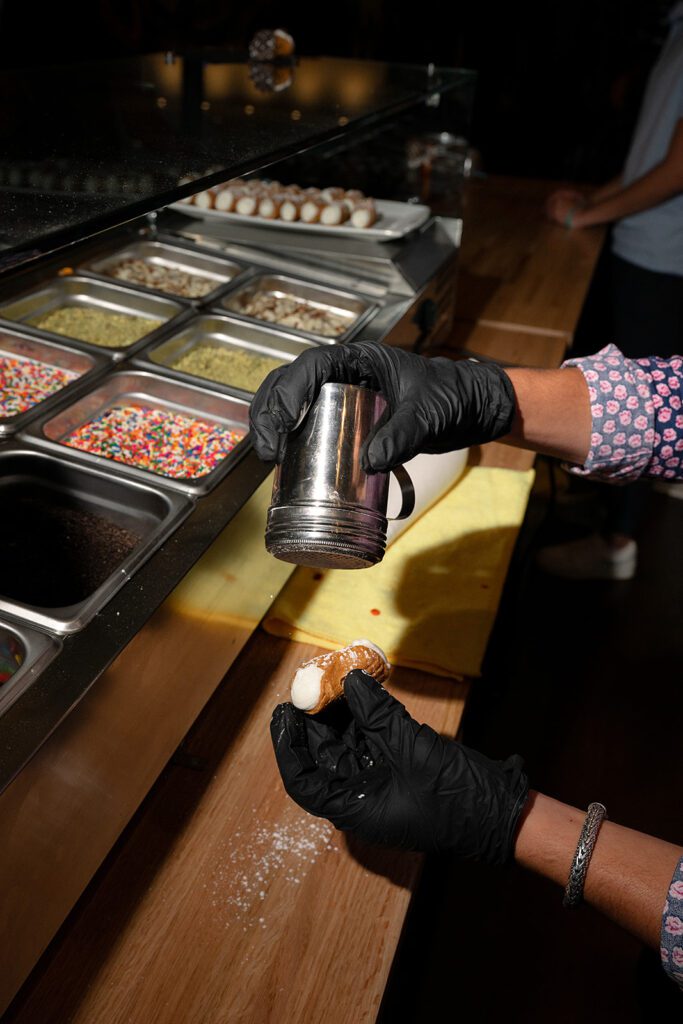 Attendant making a cannoli from GiGi’s Espresso & Cannoli Bar.
