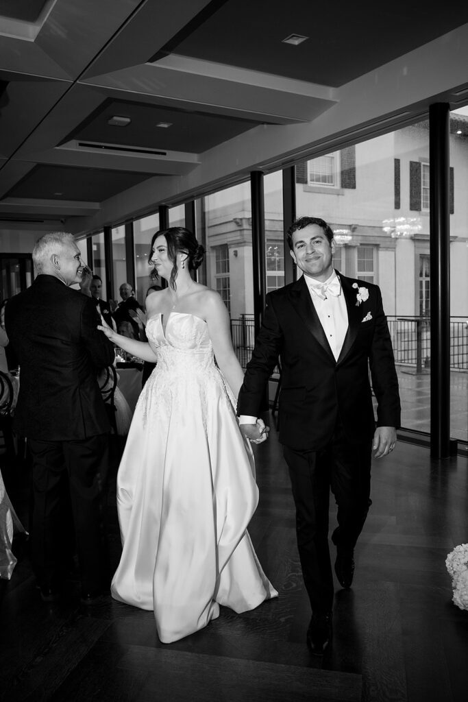 Black and white photo of the bride and groom entering their Grosse Pointe War Memorial wedding reception in The Ballroom.