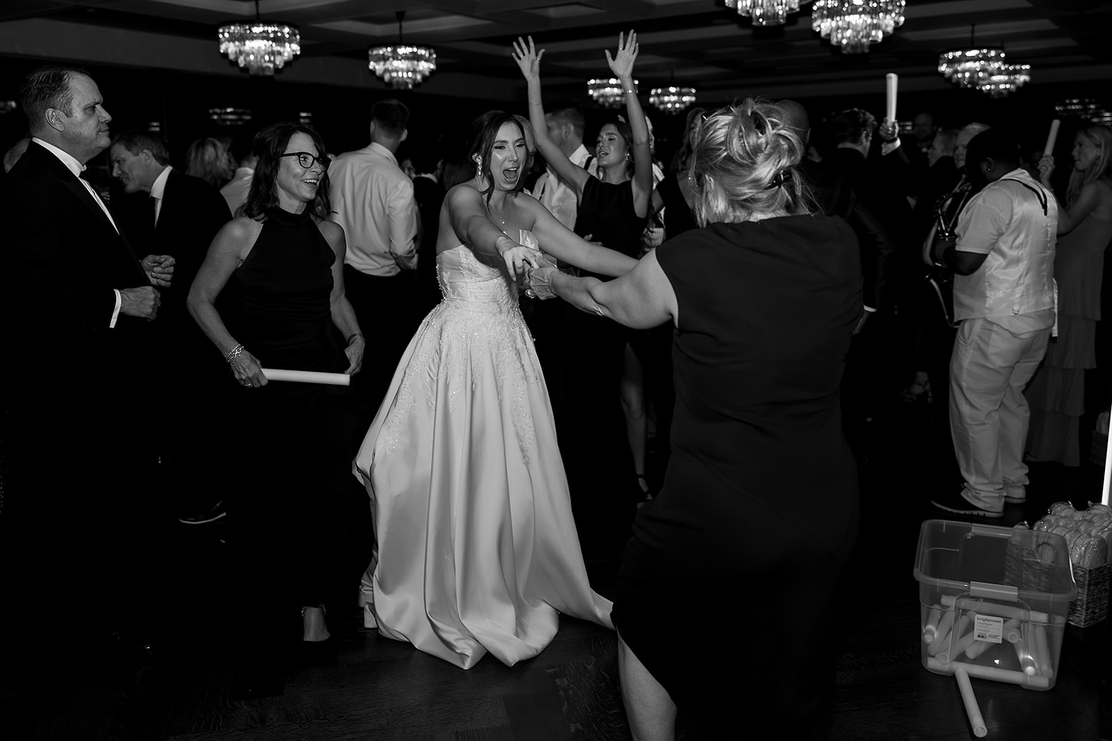 Black and white photo of a bride dancing with guests.