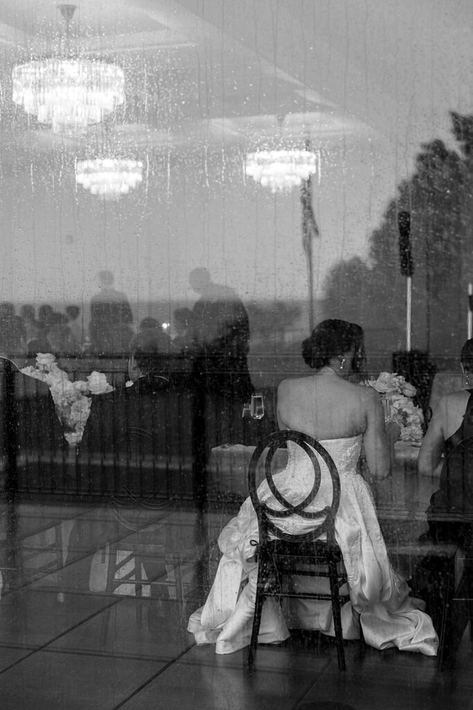 Photo through the window of a bride and groom sitting at the head table.
