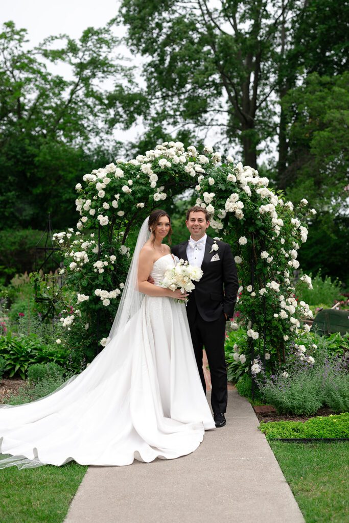 Wedding portraits of the bride and groom beneath a floral arch at The War Memorial