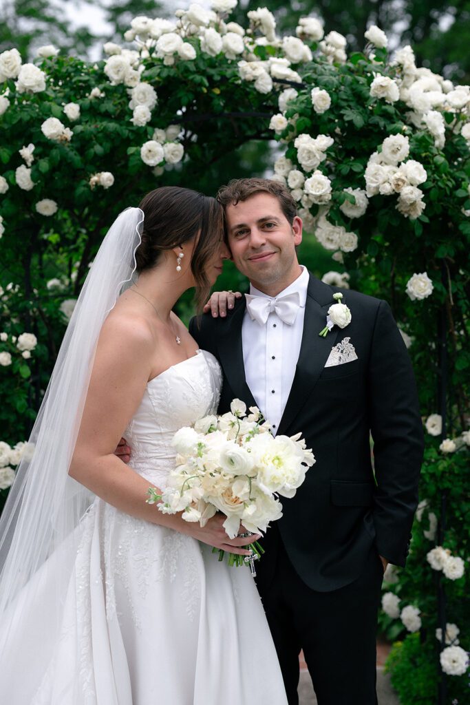 Close up shot of the bride and groom posing in front of a a floral arch at The War Memorial.