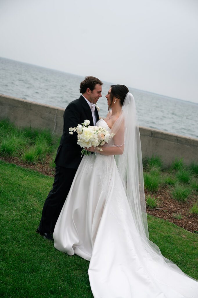Bride and groom laughing together along the waterfront at The War Memorial in Grosse Pointe Farms.