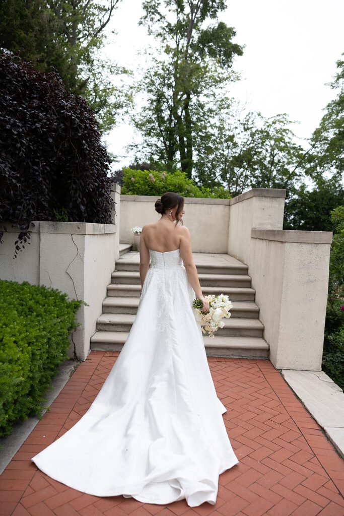 Bride posing for portraits in front of the stairs at The War Memorial in Grosse Pointe Farms in Michigan.