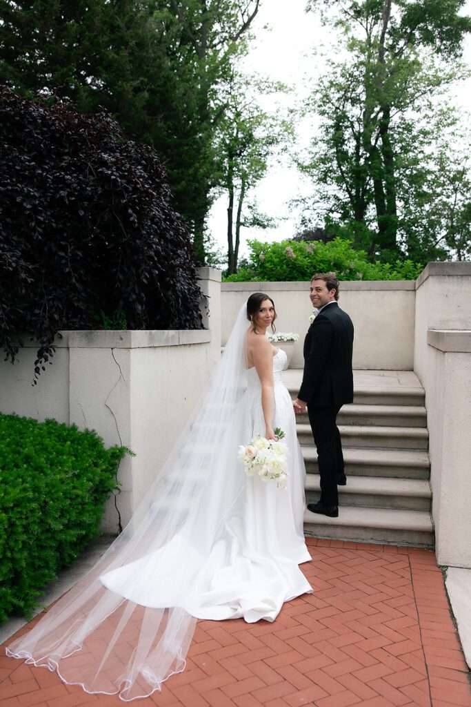 Bride and groom walking up the stairs for portraits at The War Memorial in Grosse Pointe Farms in Michigan.