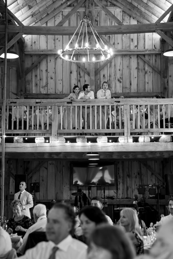 Wedding guests watching the reception from the barn loft at Noverr Farms in Traverse City, Michigan.