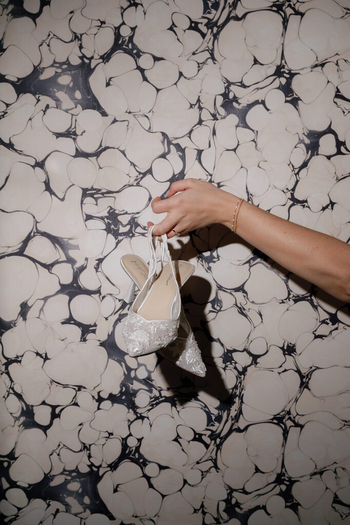 Bride’s wedding shoes photographed against patterned wallpaper during Shinola Hotel getting ready.