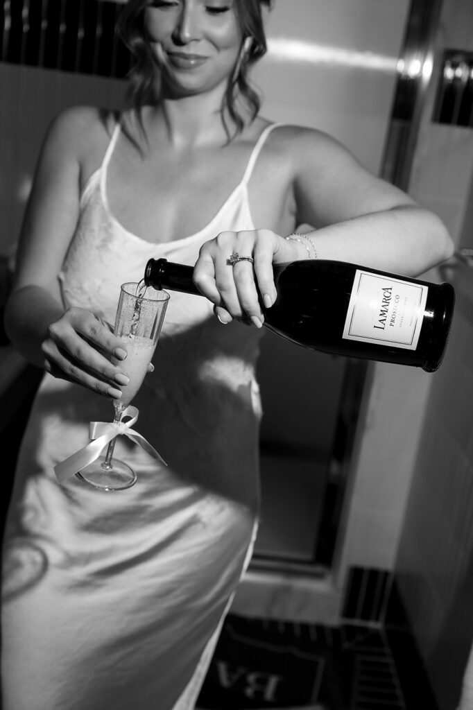Bride pouring champagne while getting ready at the Shinola Hotel before her Detroit wedding.