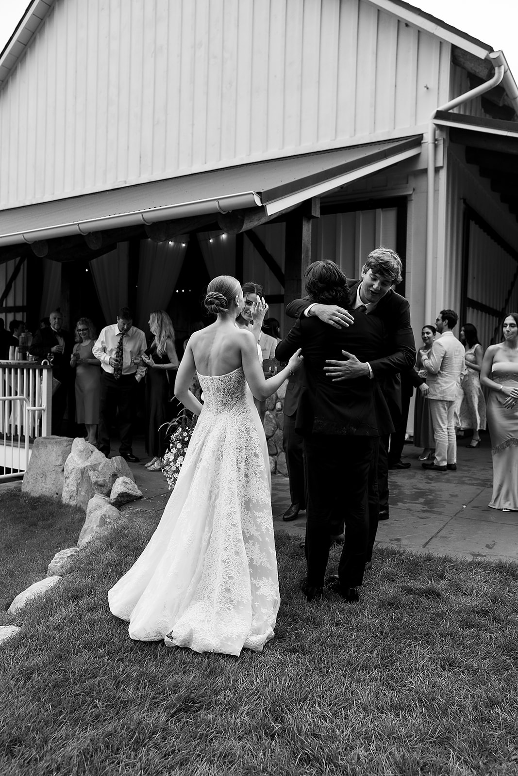 Bride and groom greeting guests during cocktail hour outside the barn at Noverr Farms in Traverse City, Michigan.