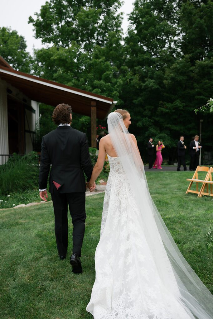 Candid photo of a bride and groom walking hand in hand back to the wedding venue.