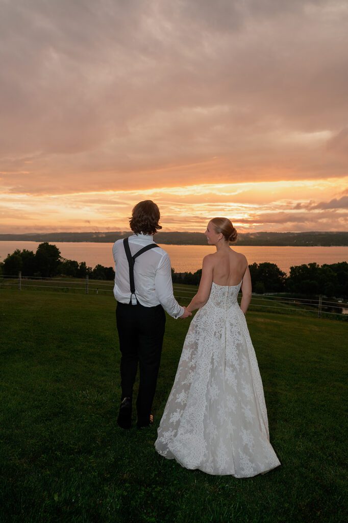 Bride and groom standing together overlooking Lake Leelanau at sunset during their Northern Michigan wedding.