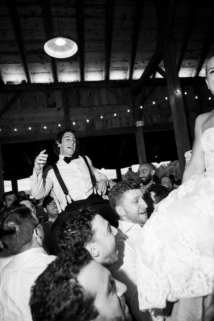 Bride and groom being lifted up in chairs during the reception.
