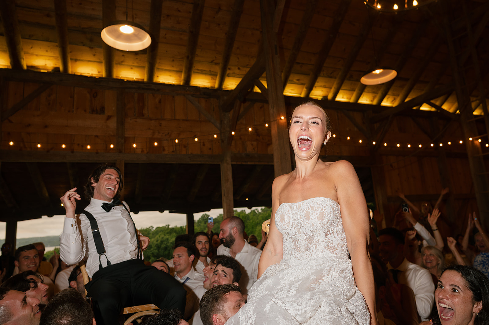 Bride and groom being lifted in the air on chairs during their reception.