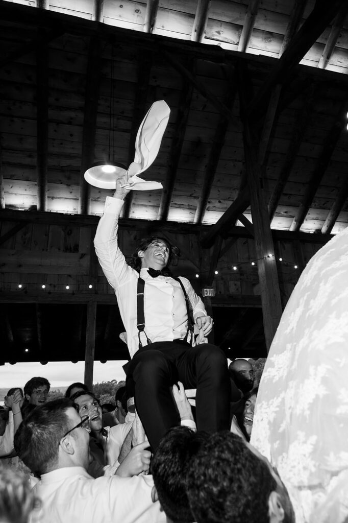 Groom being lifted in the air during the reception and waving his towel.