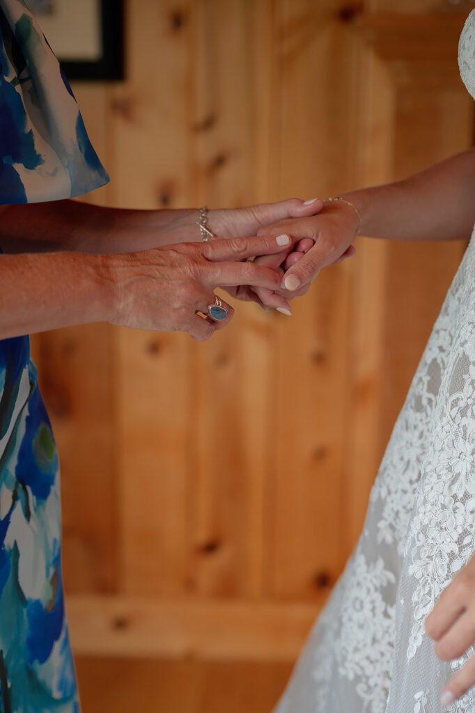 Close up shot of a bride and her mother holding hands as they get ready for the wedding.