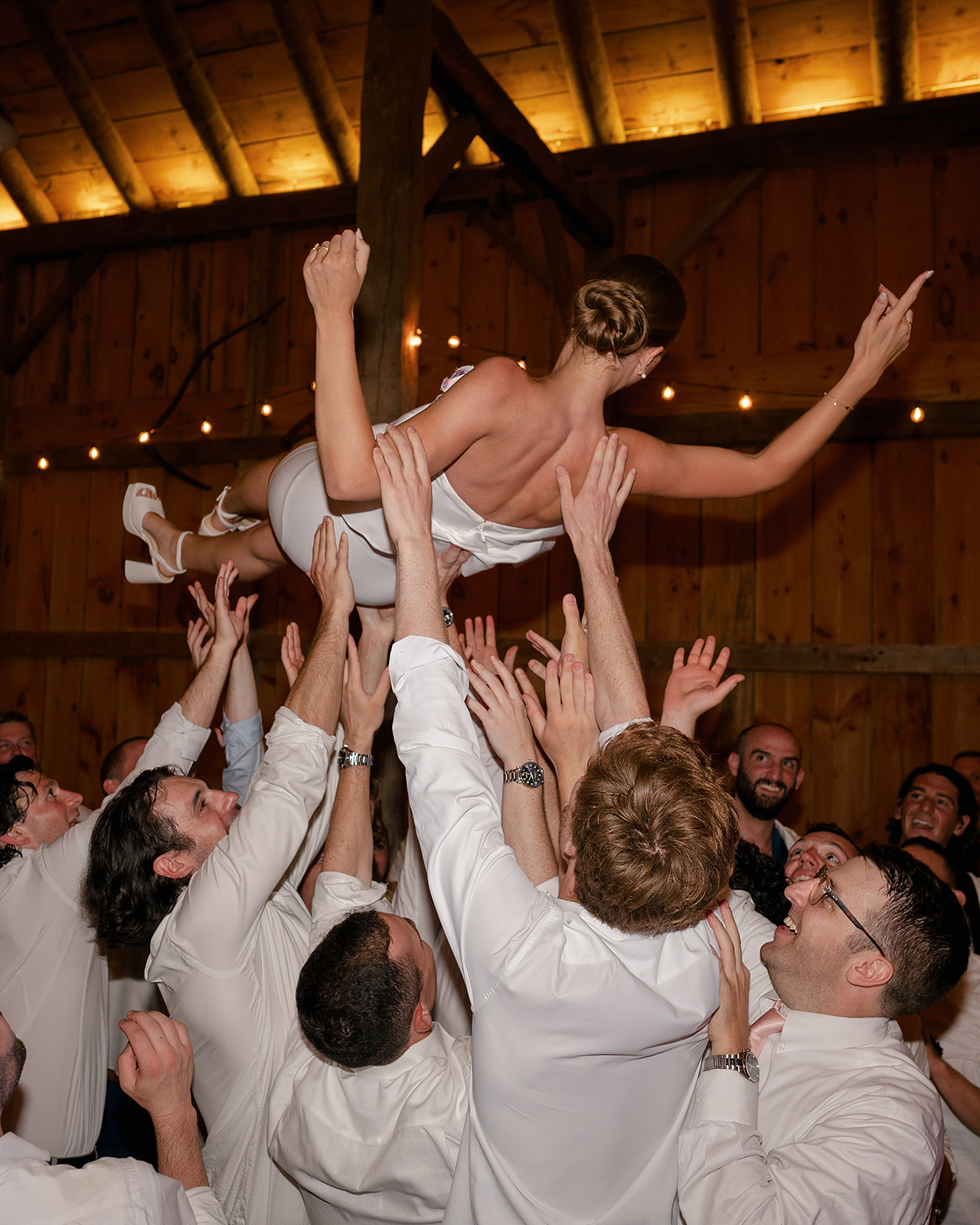 Bride being lifted up into the air by guests during a Noverr Farms wedding reception in Traverse City, Michigan.